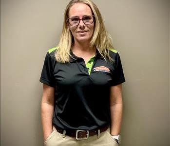 Female employee in SERVPRO uniform with long blonde hair smiling in front of grey background
