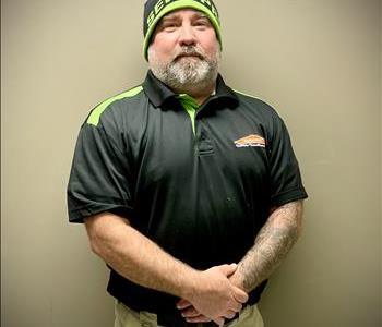 Male employee with SERVPRO uniform on posing in front of a grey background