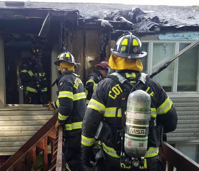 Firemen walking into a burned home