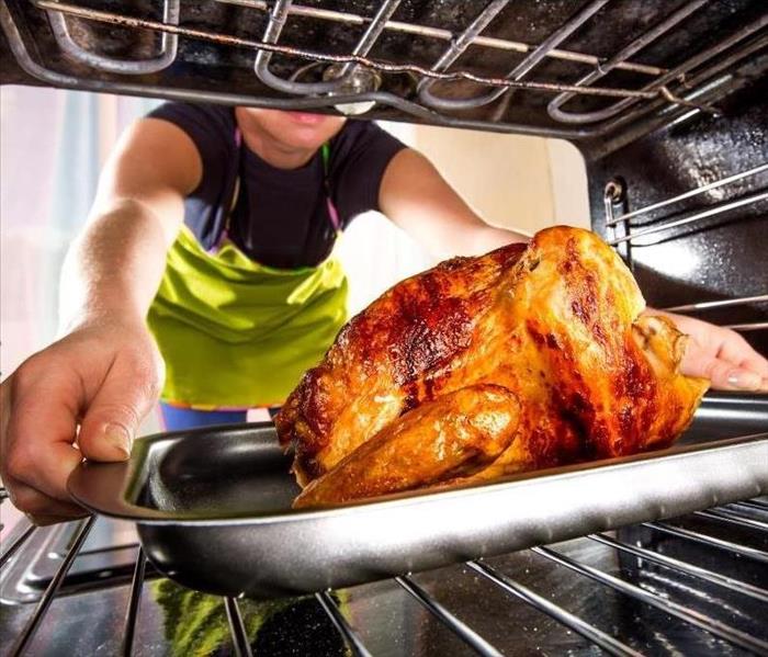 person placing turkey in oven