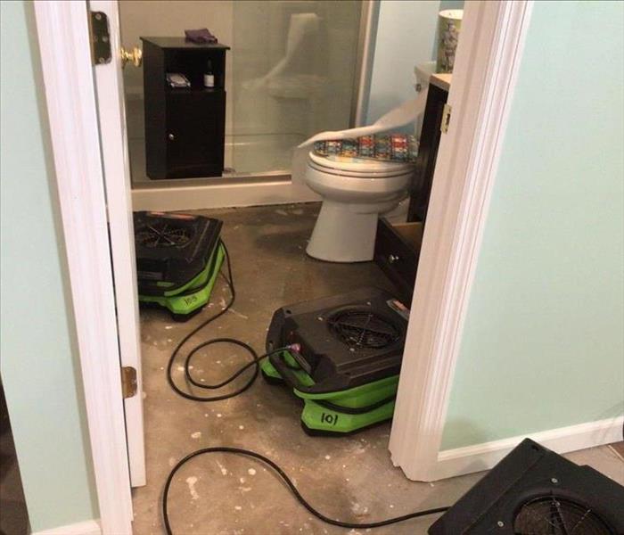 Air movers placed after demo of moisture barrier flooring in a bathroom.